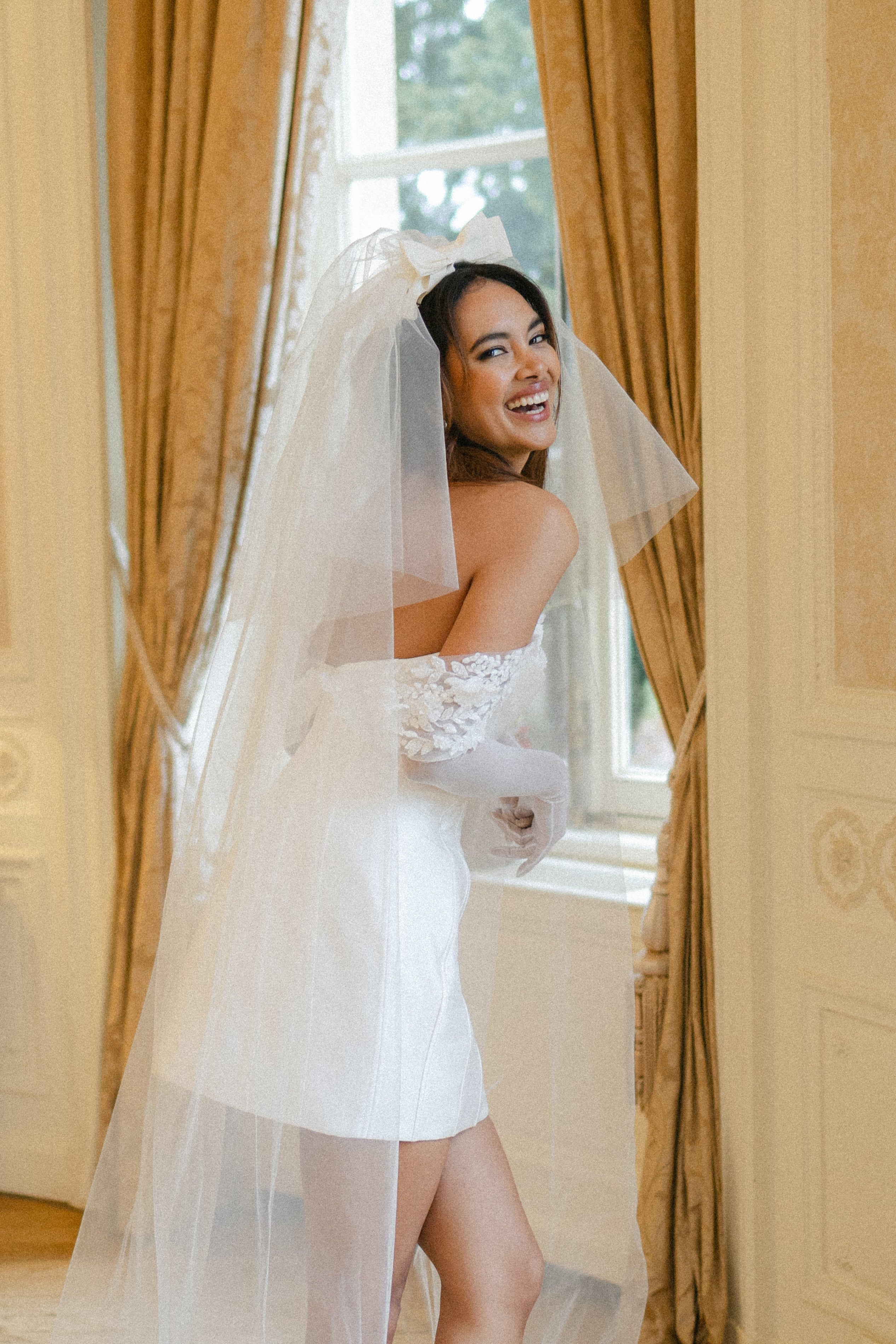 short corseted gown with beaded lace bust and straps and gloves with a double tier wedding bow veil