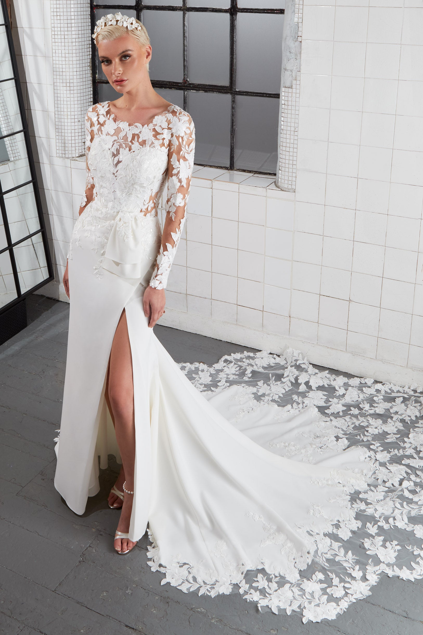 lux crepe flattering fishtail silhouette dress with illusion neckline and key-hole back with modern lace detailing, long sleeves and a daring thigh split and lace train and detachable bow